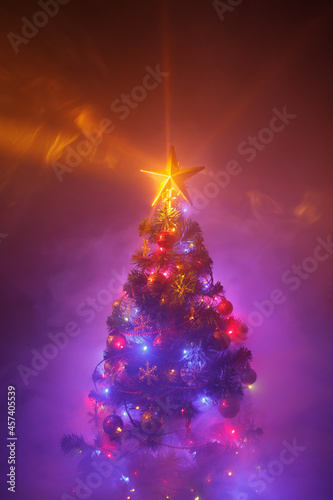Christmas tree with festive lights, purple background with smoke