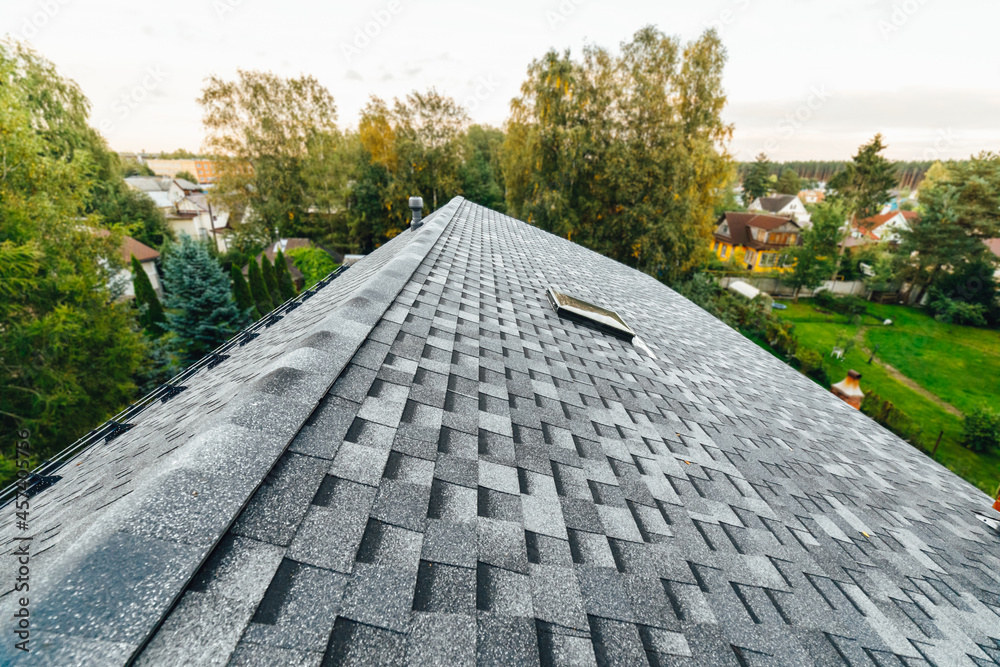 Φωτογραφία roof of new house with shingles roof-tiles, green foliage background