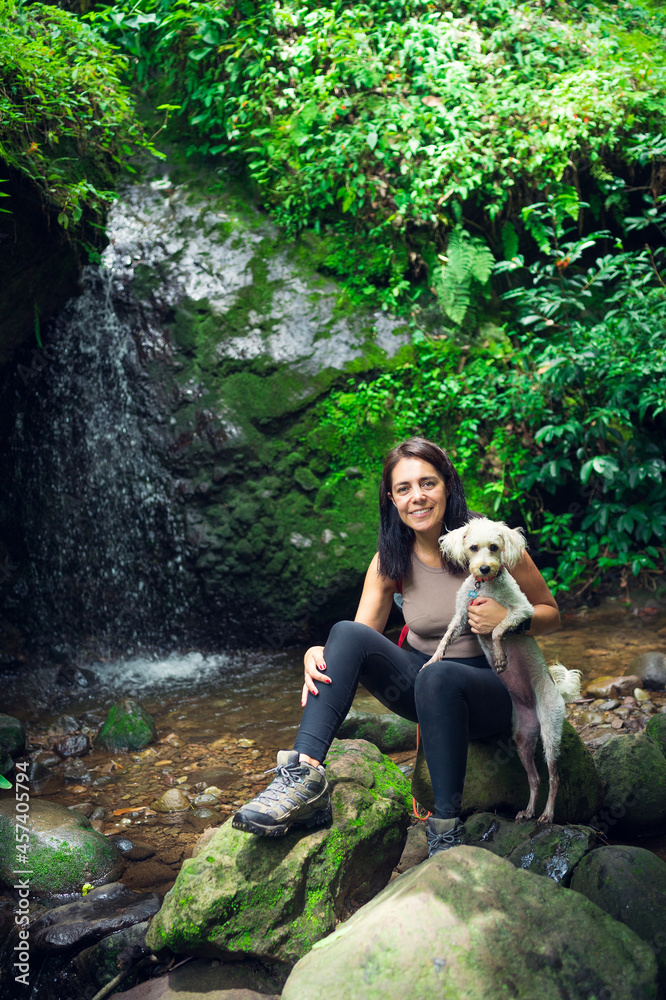 Young woman posing with her puppy in the tropical forest. Woman and pet in green wet forest on sunny day. Sustainable tourism concept. Amatlán, Mexico.