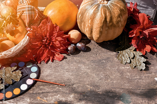 Autumn aesthetic background: yellow vegetables, fruits and bright paints with a brush, pumpkin, peach and melon. Thanksgiving Day concept. Autumn still life with red georgine, modern shadows photo