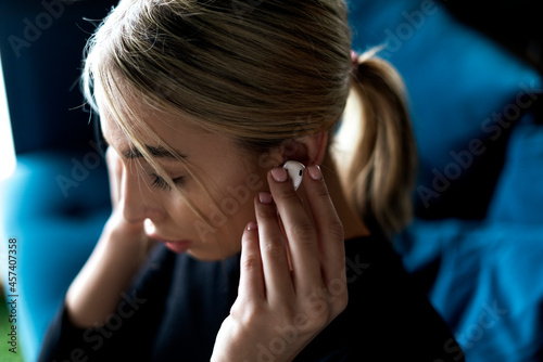 young girl listen to music in white wireless earpones or earbuds photo