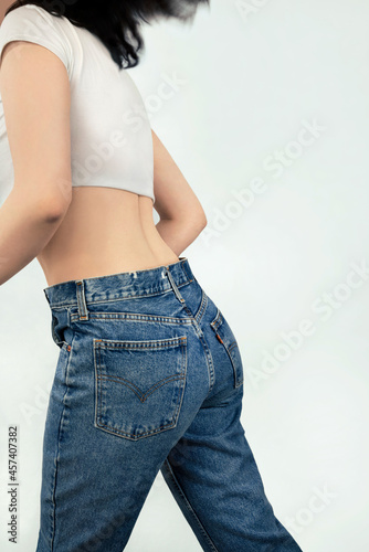 Rear view of woman in jeans running against white background