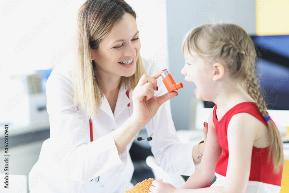 Pediatrician doctor teaching little girl to use hormonal inhaler in clinic Pediatrician doctor teaching little girl to use hormonal inhaler in clinic