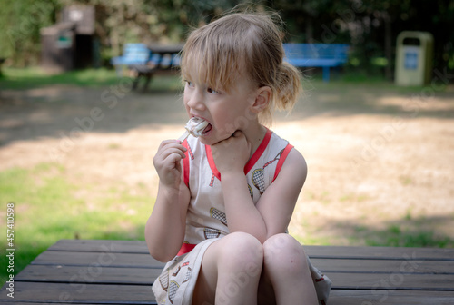 Young girl sitting on table and eating ice cream