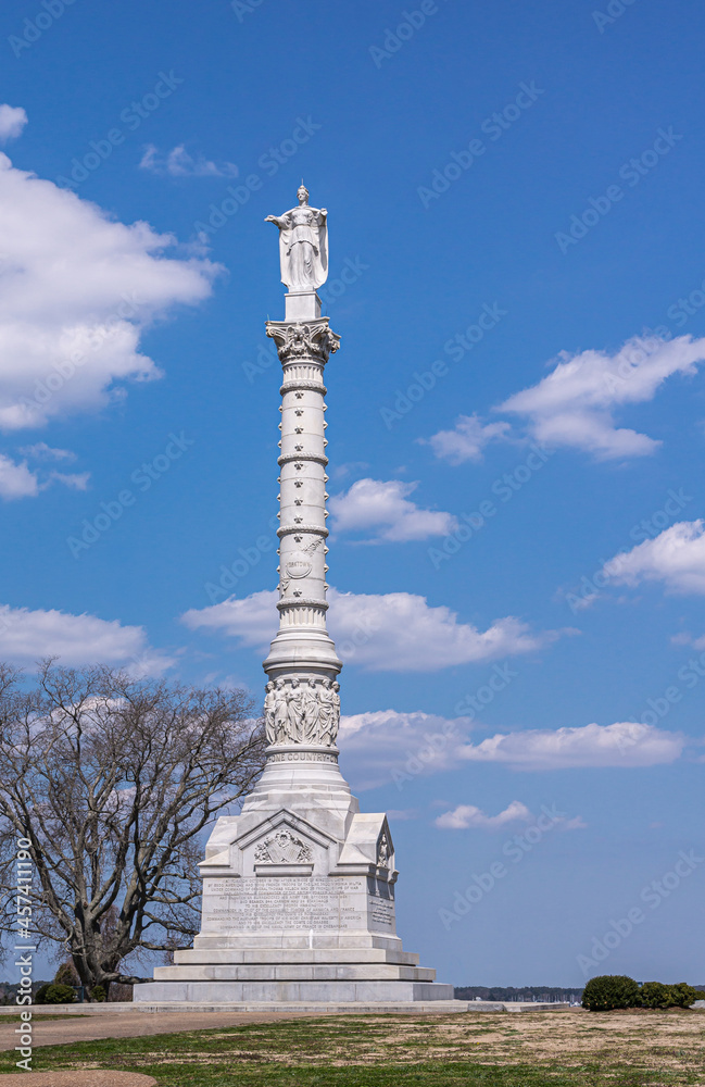 USA, Virginia, Yorktown - March 30, 2013:  Frontal view, Yorktown Victory Monument , complete white stone memorial with statues against blue sky, stands on green-brown hill.