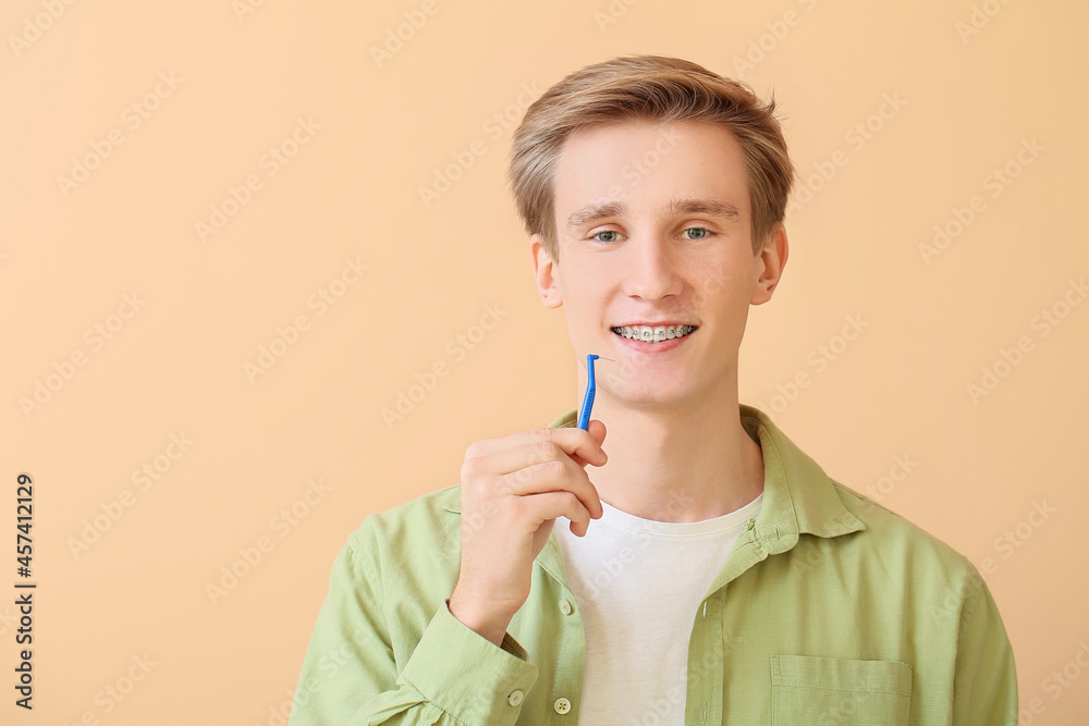 Handsome man with dental braces and brush on color background Handsome man with dental braces and brush on color background