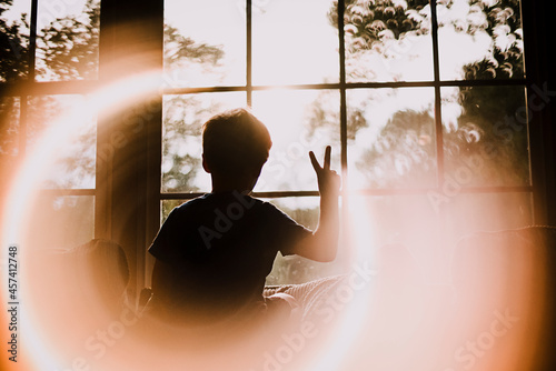 Back of Young Boy in Window Making Peace Sign With Circle Light Effect photo