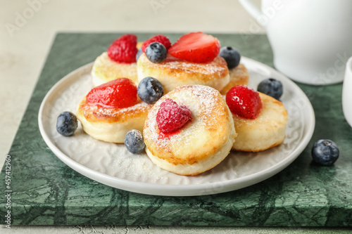 Plate with tasty cottage cheese pancakes and berries on table