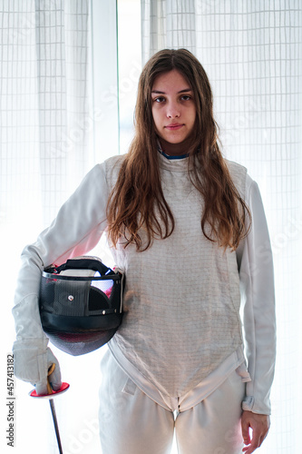 Portrait of a young fencer girl with mask and foil in hand photo