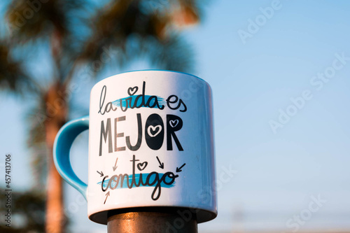 small mug with thoughtful phrase, outdoors, mug on the street, background of blue sky and palm tree. beach background. reflection and love concept. sublimation photo