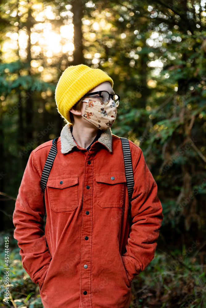 Young person standing in forest wearing mask during global pandemic
