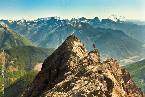 Mountain climber stands on mountain summit in British Columbia, Canada photo