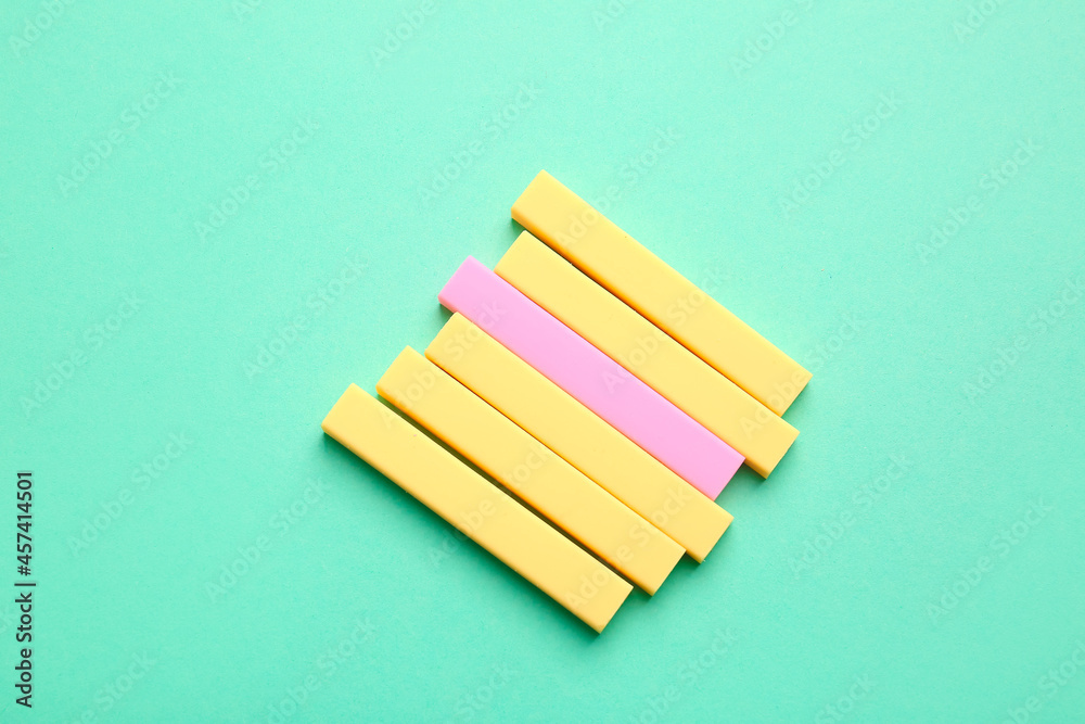 Pink eraser among yellow ones on color background. Concept of uniqueness Pink eraser among yellow ones on color background. Concept of uniqueness