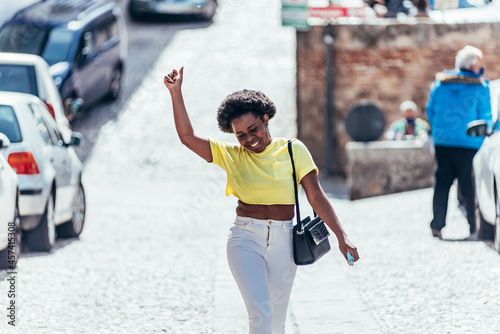 Black girl with afro hair dancing down the street in the city. photo