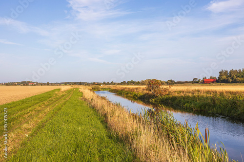 Beautiful autumn nature landscape view. Small river along field merging to blue sky. Sweden. 