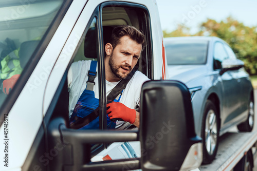 Handsome middle age man working in towing service on the road. Roadside assistance concept.