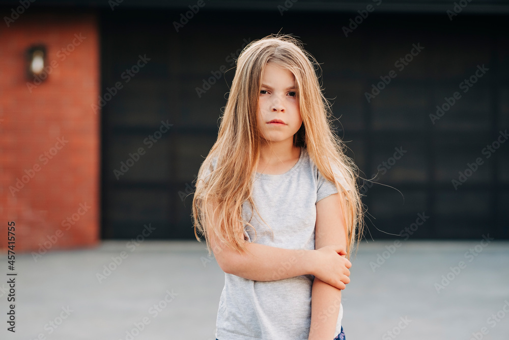Young girl standing outside in front of garage door Young girl standing outside in front of garage door