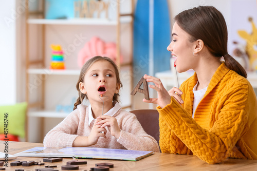 Speech therapist working with cute girl in clinic photo