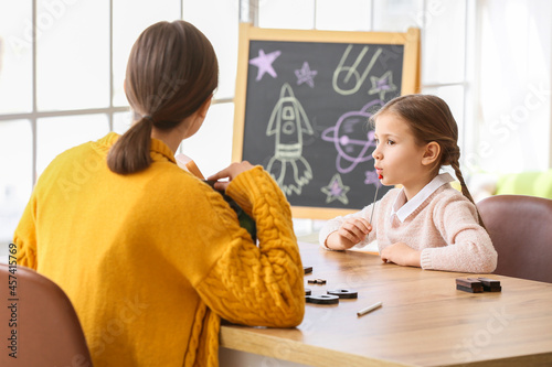 Speech therapist working with cute girl in clinic photo