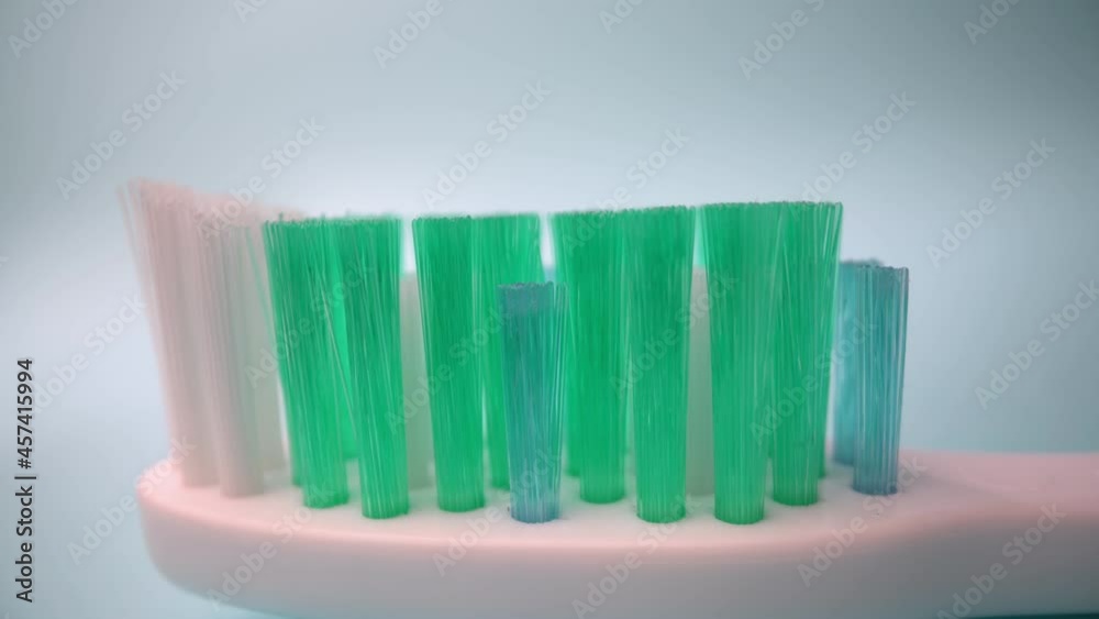 Extreme macro video filming, toothbrush on a blue background in motion, Applying toothpaste to the brush.. Close-up. Extreme macro video filming, toothbrush on a blue background in motion, Applying toothpaste to the brush.. Close-up.