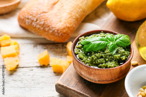 Bowl with tasty pesto sauce  bread and cheese on light wooden background  closeup
