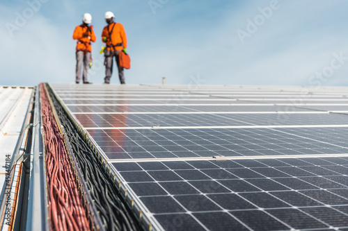 Solar panel installation with unrecognizable technicians on top