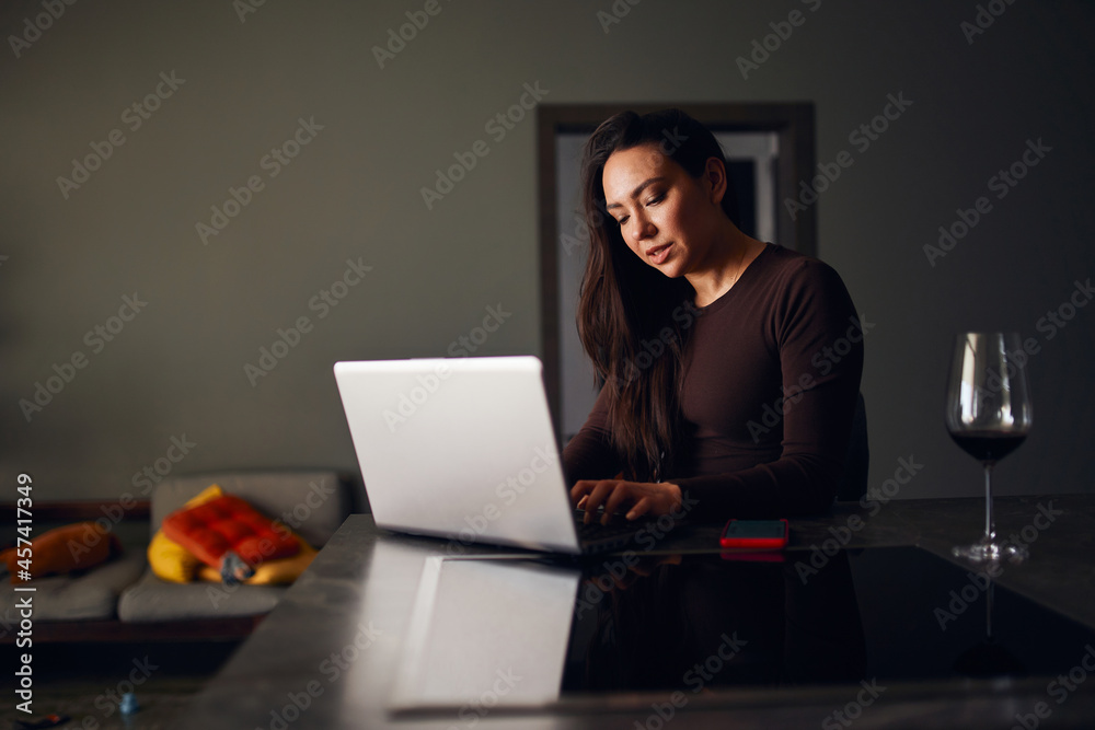 Brunette woman drinking wine and using laptop Brunette woman drinking wine and using laptop