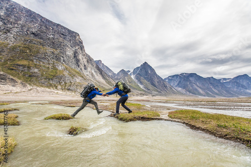 Backpackers work together to cross a river channel. photo