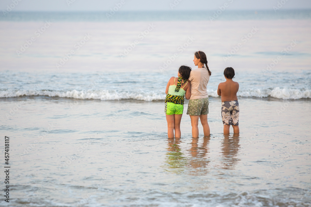 Mother and children from behind watching sunset at beach Mother and children from behind watching sunset at beach