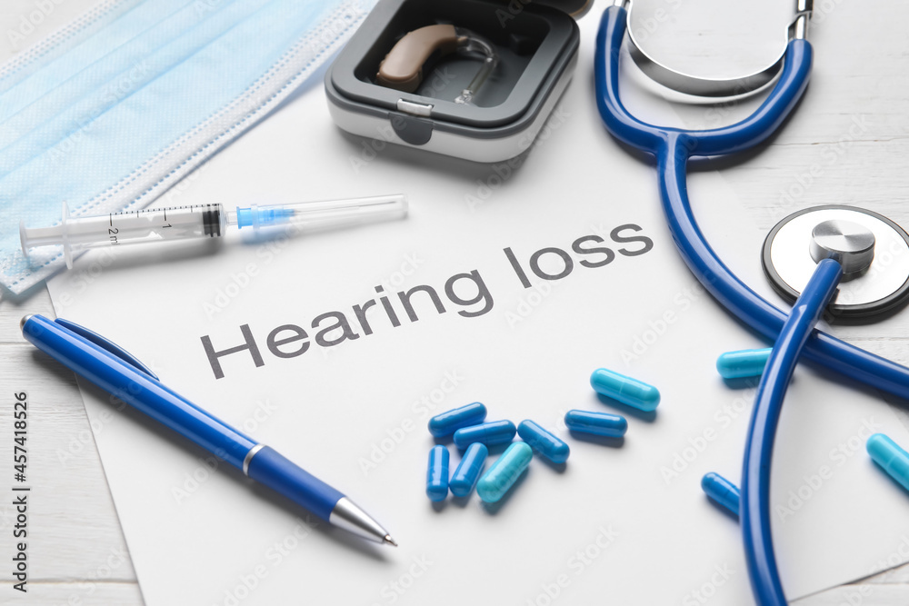 Text HEARING LOSS with stethoscope and pills on white wooden background, closeup Text HEARING LOSS with stethoscope and pills on white wooden background, closeup