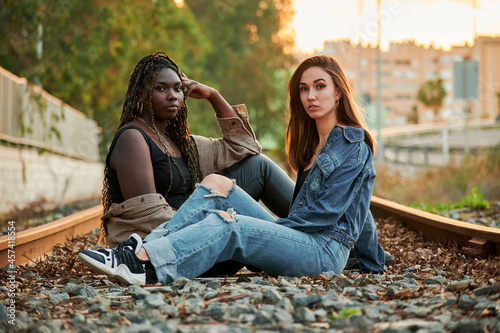 Two multi-ethnic young women pose and look at the camera at sunset photo