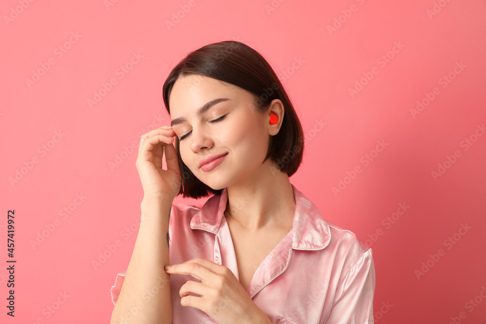 Young woman with ear plug on pink background Young woman with ear plug on pink background