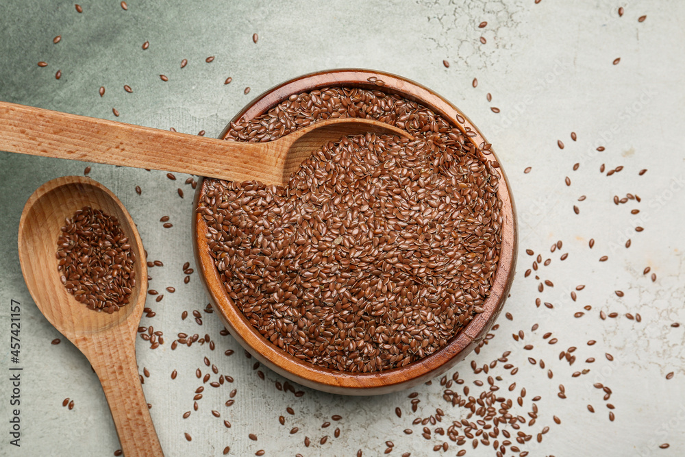 Bowl and spoons with flax seeds on color background Bowl and spoons with flax seeds on color background