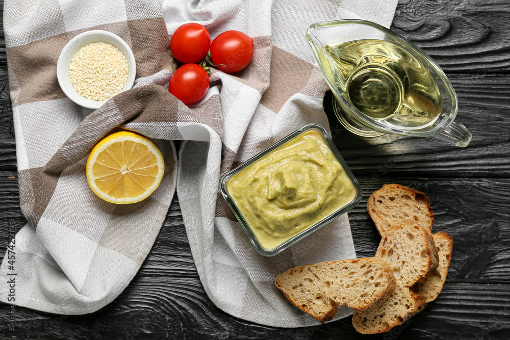 Bowl with tasty baba ghanoush and fresh products on dark wooden background