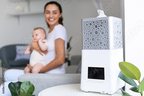 Фотография Modern humidifier in room with mother and her baby