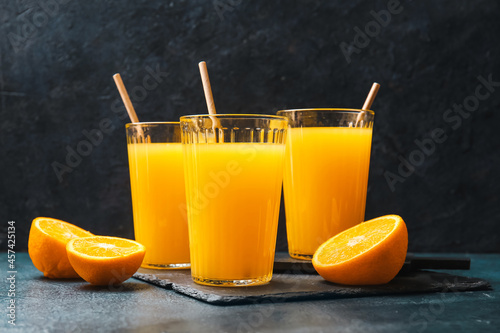 Glasses of tasty orange juice on dark background