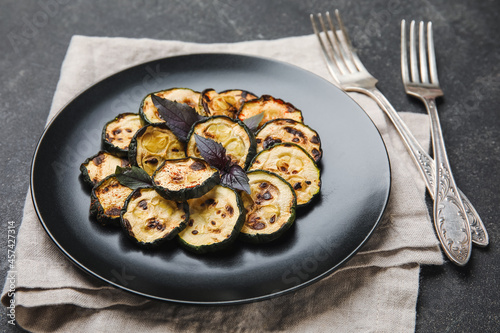 Plate with tasty grilled zucchini on dark background