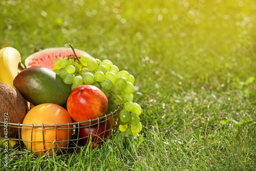 Basket with fresh fruits on grass, closeup