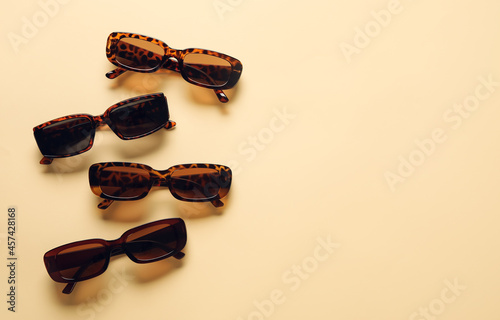 Stylish female sunglasses on color background photo