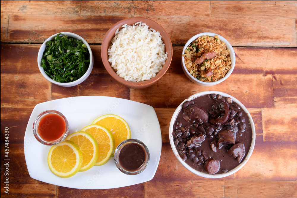 delicious Brazilian food feijoada with beans, pork, bacon, sausage with cabbage, rice, salad, spices and pepper. rustic cuisine. delicious Brazilian food feijoada with beans, pork, bacon, sausage with cabbage, rice, salad, spices and pepper. rustic cuisine.