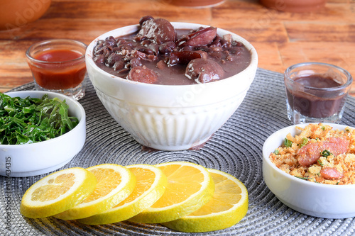 delicious Brazilian food feijoada with beans, pork, bacon, sausage with cabbage, rice, salad, spices and pepper. rustic cuisine.