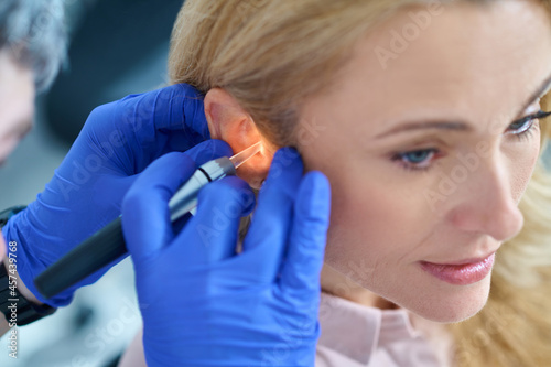 Hands in gloves with luminous device near womans ear