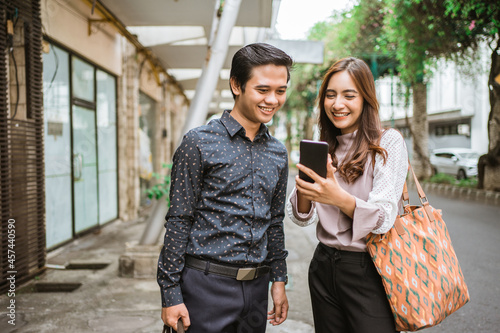 attractive business woman showing her mobile phone screen to her partner