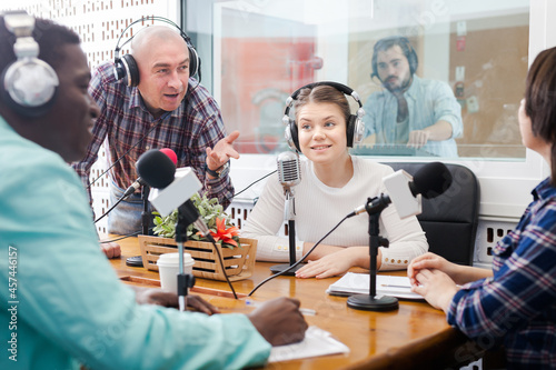 Adult presenters of different nationalities in sound broadcasting station hosting live radio show