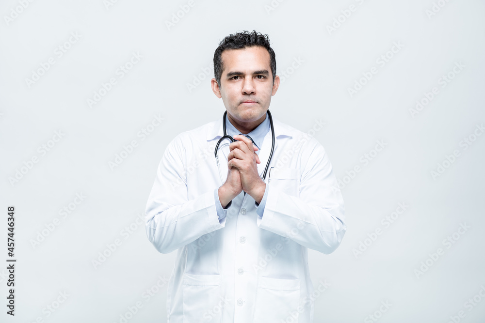 Portrait of a cheerful smiling man doctor praying hands folded and looking into the camera on white background. Portrait of a cheerful smiling man doctor praying hands folded and looking into the camera on white background.