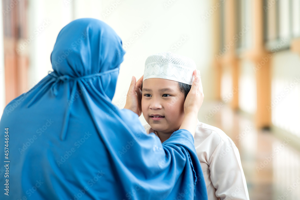 Concept Eid mubarak, A picture of an Islam Muslim boy chasing his mother with love, and the mother helped take care of his hat at the mosque after prayer.
