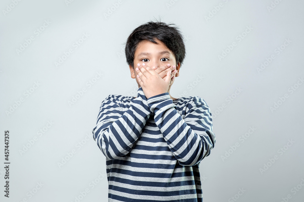 Portrait of a cute Asian boy shocked covering his mouth with his hands for the mistake. Secret concept, on white background. Portrait of a cute Asian boy shocked covering his mouth with his hands for the mistake. Secret concept, on white background.