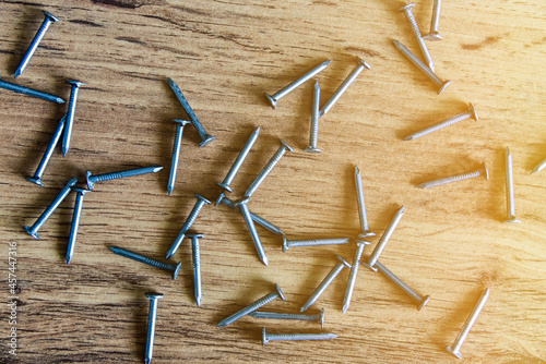 A pile of thin metal nails scattered on a wooden surface