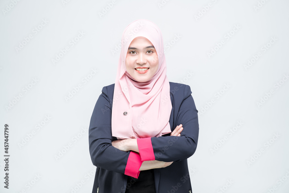 An office worker for an Asian Muslim woman stands with arms crossed with a happy face and a commitment to work, on white background. An office worker for an Asian Muslim woman stands with arms crossed with a happy face and a commitment to work, on white background.