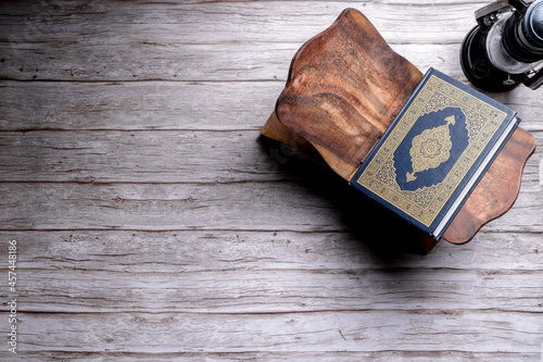 Foto Islamic concept - The Holy Al Quran with written Arabic calligraphy meaning of Al Quran, on wooden stand, with copy space
